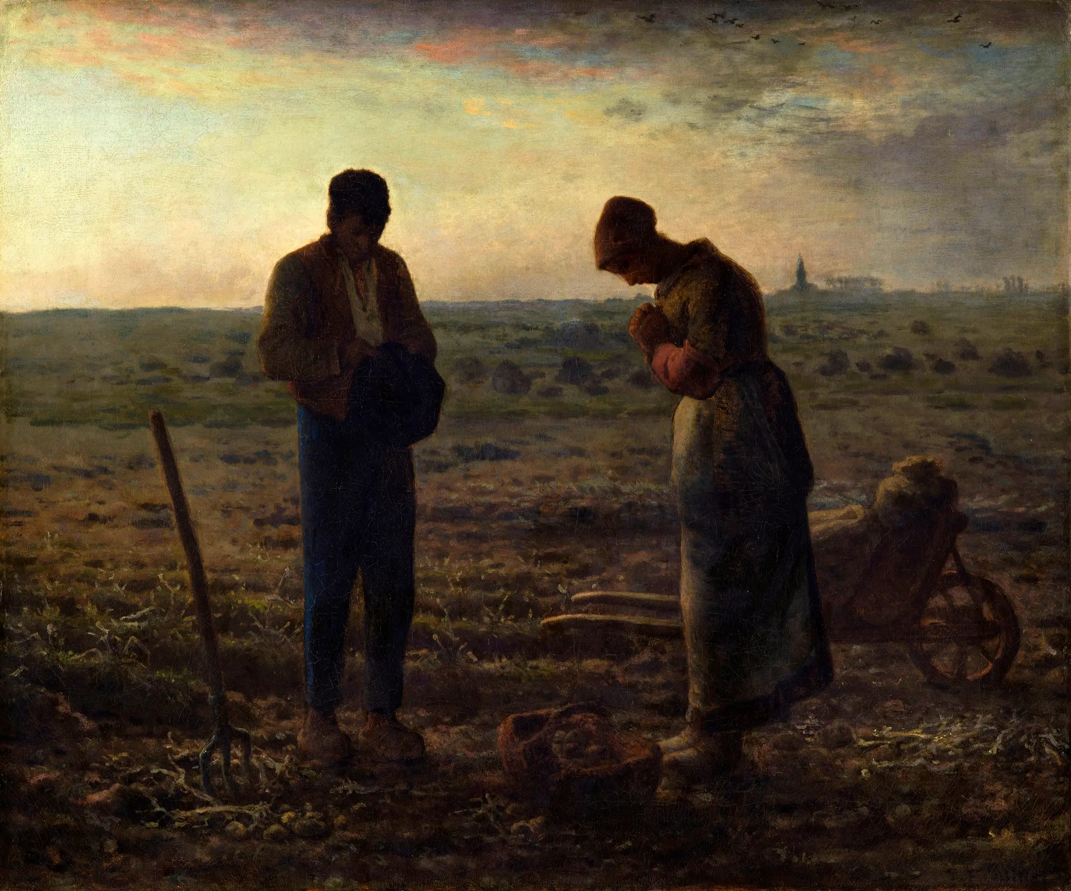 In the fading light of evening over open farmland, a man and a woman pause from digging potatoes and stand with heads bowed in prayer, a pitchfork planted in the earth beside them, while the distant church tower on the horizon rings the Angelus bell.